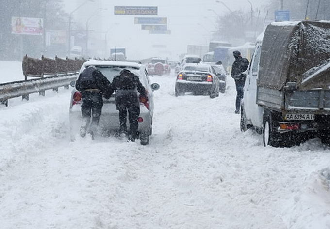 Motorists push a car that is stuck in snow during a blizzard in Ukrainian capital Kiev